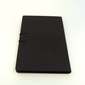 May include: A black, rectangular notebook with a simple design and a black elastic closure.