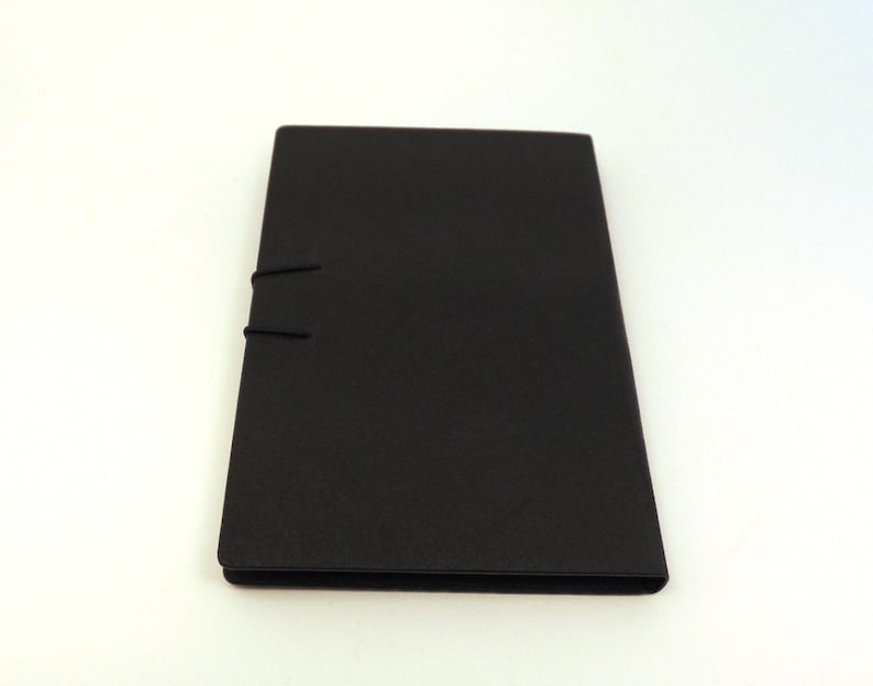 May include: A black, rectangular notebook with a simple design and a black elastic closure.