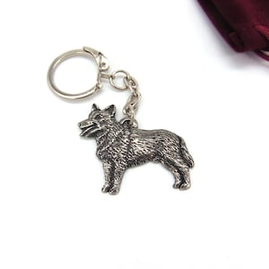 May include: A silver metal keychain featuring a detailed wolf silhouette. The keychain has a silver ring and chain.
