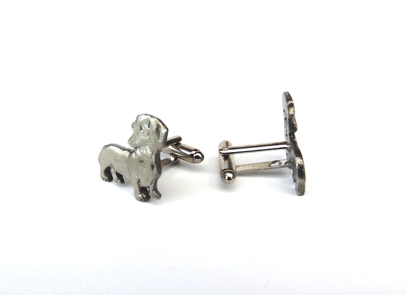 Puede incluir: Un par de gemelos de plata con la silueta de un dachshund. Los gemelos est&aacute;n hechos de metal y tienen un acabado pulido.