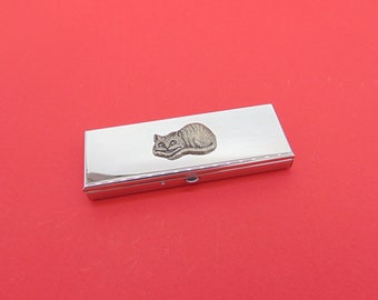 May include: A silver metal pill box with a small, detailed pewter cat design on the lid.