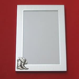May include: A silver picture frame with a raised design of a cowboy boot and hat in the bottom right corner.