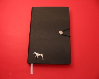 May include: A black leather journal with a silver dog silhouette and a silver button closure. The journal has a white ribbon bookmark.