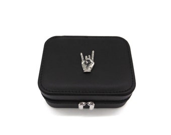 May include: Black faux leather jewelry box with a silver rock and roll hand symbol on the lid.
