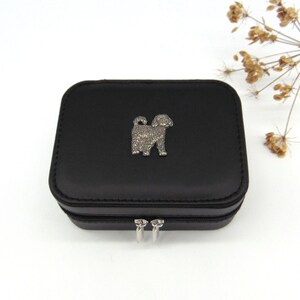 May include: Black jewellery box with a silver dog charm on the lid. The box has a zipper closure.