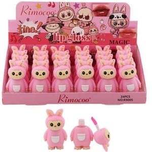 Peut inclure: Une boîte de présentation contenant 24 tubes de brillant à lèvres roses en forme de lapins de dessin animé avec des oreilles. La boîte affiche le texte Rimocoo, fine, lip gloss et MAGIC, ainsi que des illustrations de lapins et de lèvres.