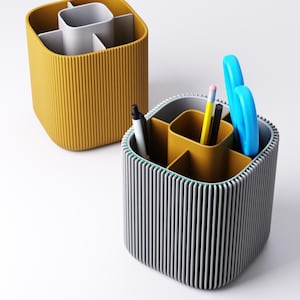 May include: Two desk organizers with vertical ribbed sides. One is mustard yellow, the other is gray with a green trim. The gray organizer holds pens, a pencil, and blue scissors. Both have interior compartments.