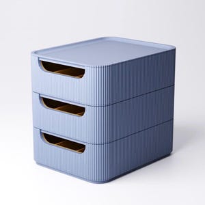May include: A stackable storage unit in a soft blue hue. The unit has three drawers with integrated handles and a ribbed texture on the exterior. The interior of the drawers is a warm, golden color.