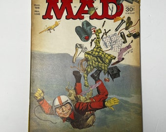 May include: Vintage MAD Magazine cover featuring Alfred E. Neuman in a red jumpsuit and helmet, mid-air. The cover includes the magazine's title in large red letters, issue details, and floating objects.