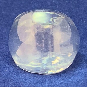 Peut inclure: Un objet en verre clair et arrondi avec des reflets irisés. L'objet a une surface lisse et polie et réfléchit la lumière, créant un subtil effet arc-en-ciel. La forme rappelle une petite sphère aplatie.