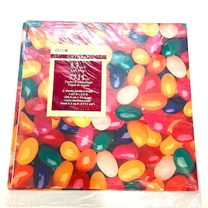 Peut inclure: Papier cadeau avec un motif de bonbons gélifiés aux couleurs vives : rouge, rose, orange, jaune, vert, bleu et blanc. L'emballage comprend une étiquette avec le texte "CLEO GIFTWRAP" et des détails sur la taille des feuilles (50,8 cm x 76,2 cm).