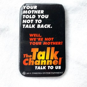 Puede incluir: Un botón negro rectangular con esquinas redondeadas. El botón presenta texto blanco y naranja: "YOUR MOTHER TOLD YOU NOT TO TALK BACK. WELL, WE'RE NOT YOUR MOTHER! The Talk Channel TALK TO US."