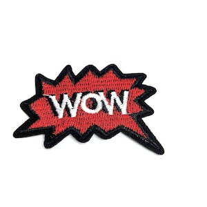 Puede incluir: Un parche bordado rojo en forma de explosión con la palabra "WOW" en blanco. El parche tiene un borde negro. Está diseñado para ser cosido o planchado sobre ropa o accesorios.