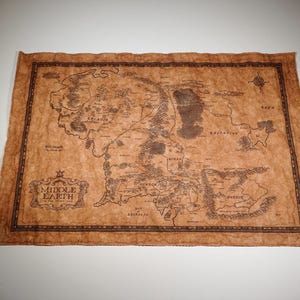 May include: A detailed map of Middle Earth, featuring intricate geographical details and place names. The map is printed on a parchment-like material with a brown and sepia color scheme. The map includes a decorative border and the text "Middle Earth".