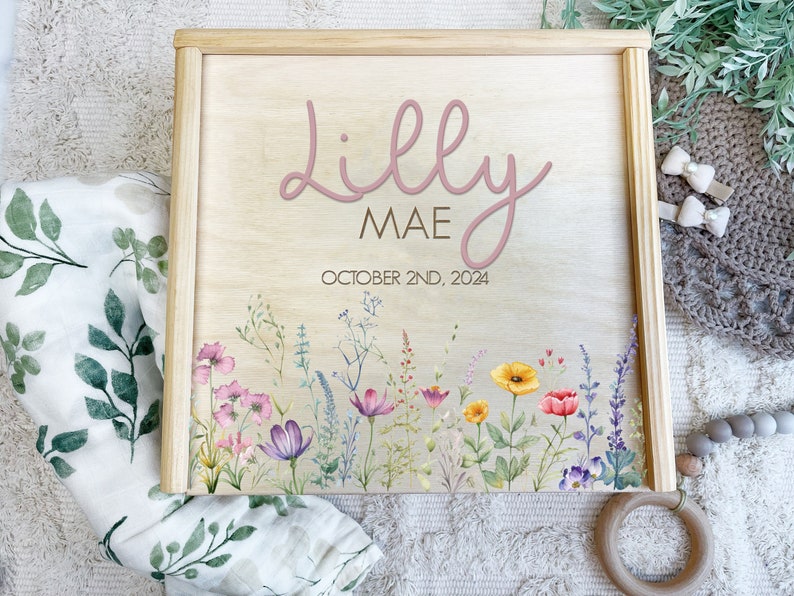 May include: A wooden box with a floral design and the name "Lilly Mae" and the date "October 2nd, 2024" written on it.