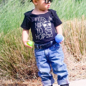 Black boy easter shirt adorned with a funny graphic featuring a bunny wearing sunglasses and text saying too hip to hop with distressed denim jeans