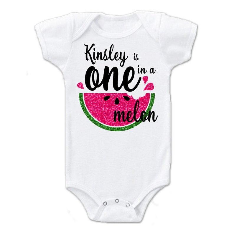 Puede incluir: Un body blanco para beb&eacute; con un gr&aacute;fico de sand&iacute;a rosa y verde y el texto "Kinsley is one in a melon".
