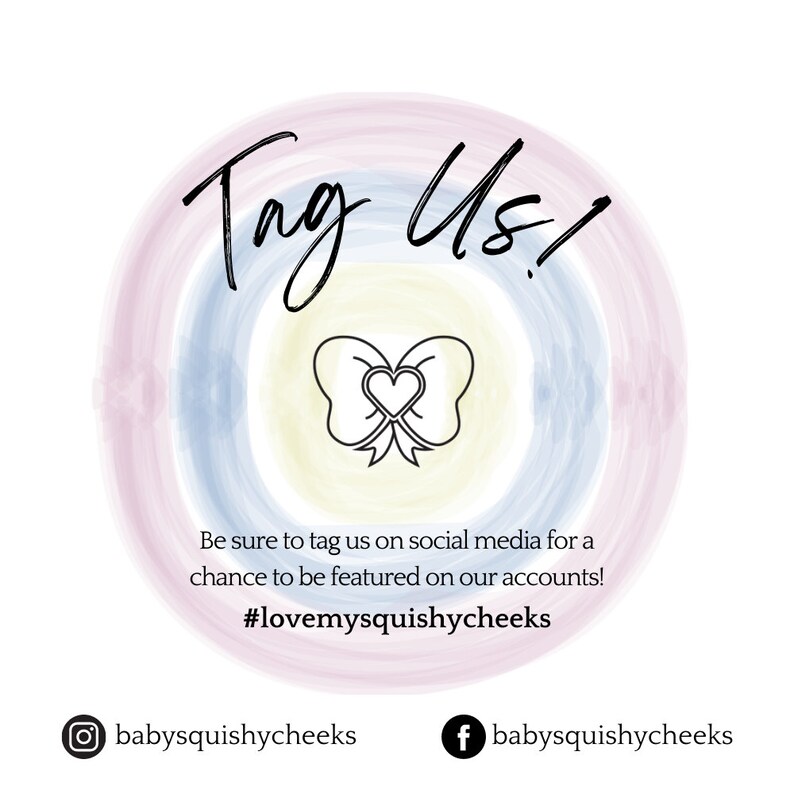 May include: A colorful graphic with a rainbow background and a bow with a heart in the center. The text "Tag Us!" is written in black cursive. The text "Be sure to tag us on social media for a chance to be featured on our accounts! #lovemysquishycheeks" is written in black. The text "babysquishycheeks" is written in black with an Instagram icon and a Facebook icon.