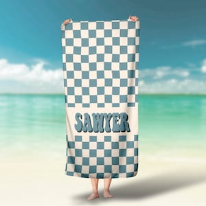 May include: A blue and white checkered beach towel with the name "Sawyer" printed in blue letters.