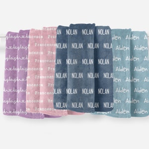May include: Five personalized fleece blankets in different colors. The blankets are arranged in a row, with the names "Laylrigh", "Francesca", "Nolan", and "Aiden" printed on them.
