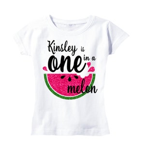 Puede incluir: Camiseta blanca con un gr&aacute;fico de sand&iacute;a y el texto "Kinsley is one in a melon".