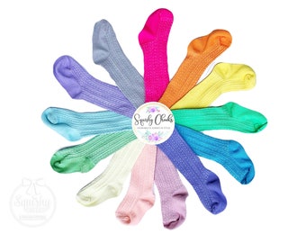 Puede incluir: Un surtido arcoíris de 10 pares de medias para bebé con textura acanalada. Las medias están dispuestas en círculo con el nombre de la marca "Squishy Chicks" en el centro.