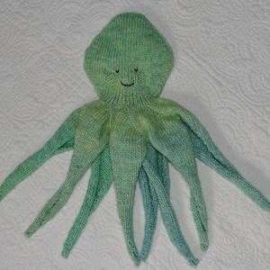 May include: A green and blue knitted octopus toy with a smiling face.