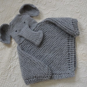 May include: A gray knitted sweater with an attached elephant-shaped hood. The hood has a gray knitted trunk and ears.