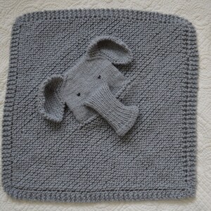 May include: A gray knitted baby blanket with a gray knitted elephant applique. The blanket has a diamond pattern and a border.