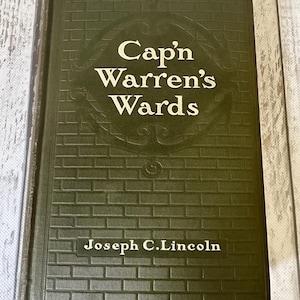May include: A green hardcover book with the title "Cap'n Warren's Wards" and the author "Joseph C. Lincoln" on the front cover.