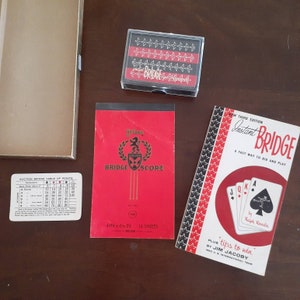 May include: A red and black bridge score pad with the text "My Tone Bridge Score" and "4 in x 6 1/2 in 16 sheets". A red and black book with the text "New Third Edition Instant Bridge A Fast Way To Bid And Play" and "Plus Tips To Win By Jim Jacoby 1963 U.S. International Team".