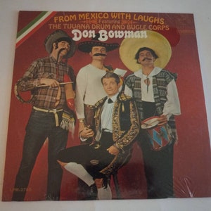 May include: A vintage vinyl record album cover featuring a group of men dressed in traditional Mexican attire. The album is titled "From Mexico With Laughs" featuring "The Tijuana Drum and Bugle Corps" and "Don Bowman".