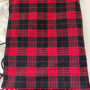 May include: Red and black plaid throw blanket with fringe.