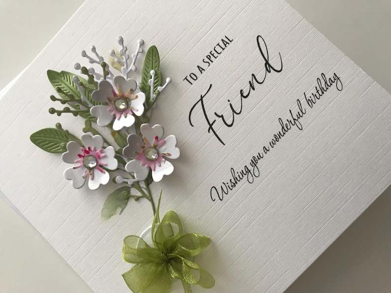 Może przedstawiać: Biała kartka z zielonymi i białymi kwiatami i zieloną kokardką. Na kartce napisano "To a special Friend Wishing you a wonderful birthday".