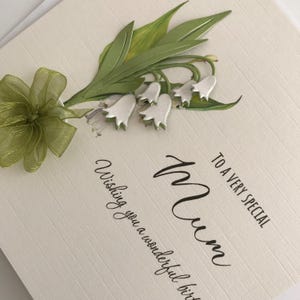 May include: A white card with a green and white floral design. The card says "To a very special Mum, Wishing you a wonderful birthday".