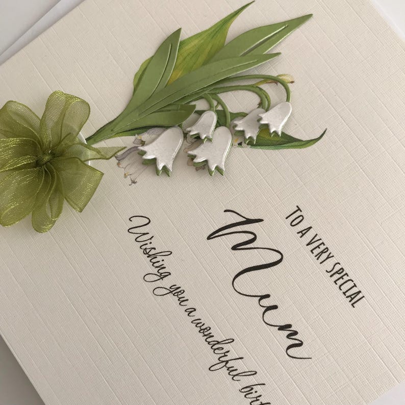 May include: A white card with a green and white floral design. The card says "To a very special Mum, Wishing you a wonderful birthday".