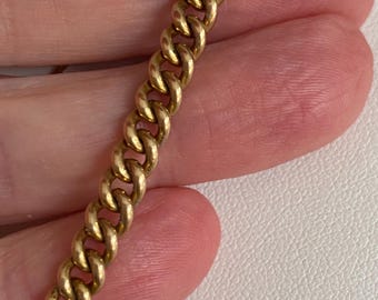 Puede incluir: Una pulsera de cadena de metal en tono dorado con un diseño clásico de eslabones tipo barbada. Los eslabones son uniformes en tamaño y forma, creando un patrón entrelazado continuo que muestra un acabado metálico pulido en toda su longitud.