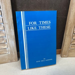May include: A blue paperback book titled "For Times Like These" by Ruby Dell Baugher.