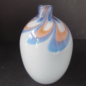 May include: A white glass vase with a swirl design in shades of blue and orange.