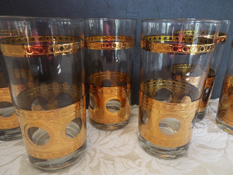May include: Set of six clear glass highball glasses with gold and amber colored bands and a gold circle design.