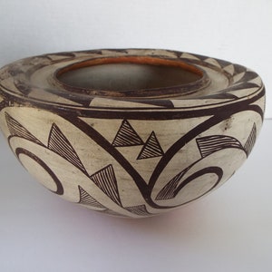 May include: A white ceramic bowl with a brown geometric design. The bowl has a wide rim and a rounded base.