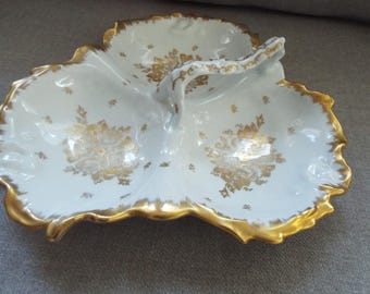 May include: A white porcelain serving dish with three sections and a gold handle. The dish is decorated with a gold floral pattern.
