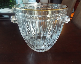May include: A clear glass ice bucket with a gold rim and two handles. The bucket has a textured, diamond-shaped pattern.