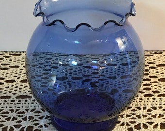 May include: A cobalt blue glass vase with a scalloped rim. The vase has a round body and a flared base.