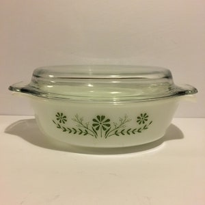 Peut inclure: Plat à gratin ovale blanc avec un couvercle en verre. Le plat est décoré d'un motif floral vert avec de petites fleurs et des feuilles.