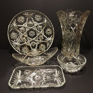 Peut inclure: Ensemble de cinq plats en verre transparent avec un motif en étoile. L'ensemble comprend une grande assiette ronde, un plat rectangulaire, un petit bol, un grand bol ovale et un vase haut.