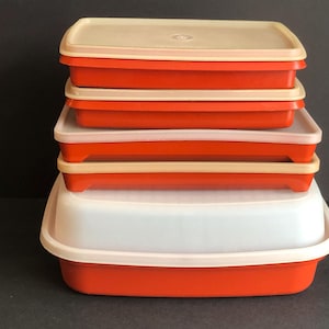 Könnte beinhalten: Ein Satz von fünf roten und weißen Plastik-Aufbewahrungsbehältern, die übereinander gestapelt sind. Die Behälter sind rechteckig und haben eine glatte, glänzende Oberfläche.