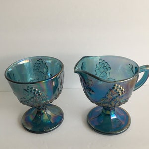 May include: A vintage blue iridescent glass creamer and sugar bowl set with a grapevine design.