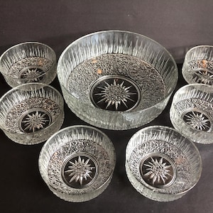 以下が含まれることがあります： 星形のテクスチャデザインが施された透明なガラスボウル7個セット。ボウルはサイズが異なり、中央に大きな丸いボウルがあります。