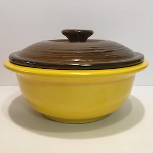 May include: A yellow ceramic casserole dish with a brown lid. The lid has a knob on top.